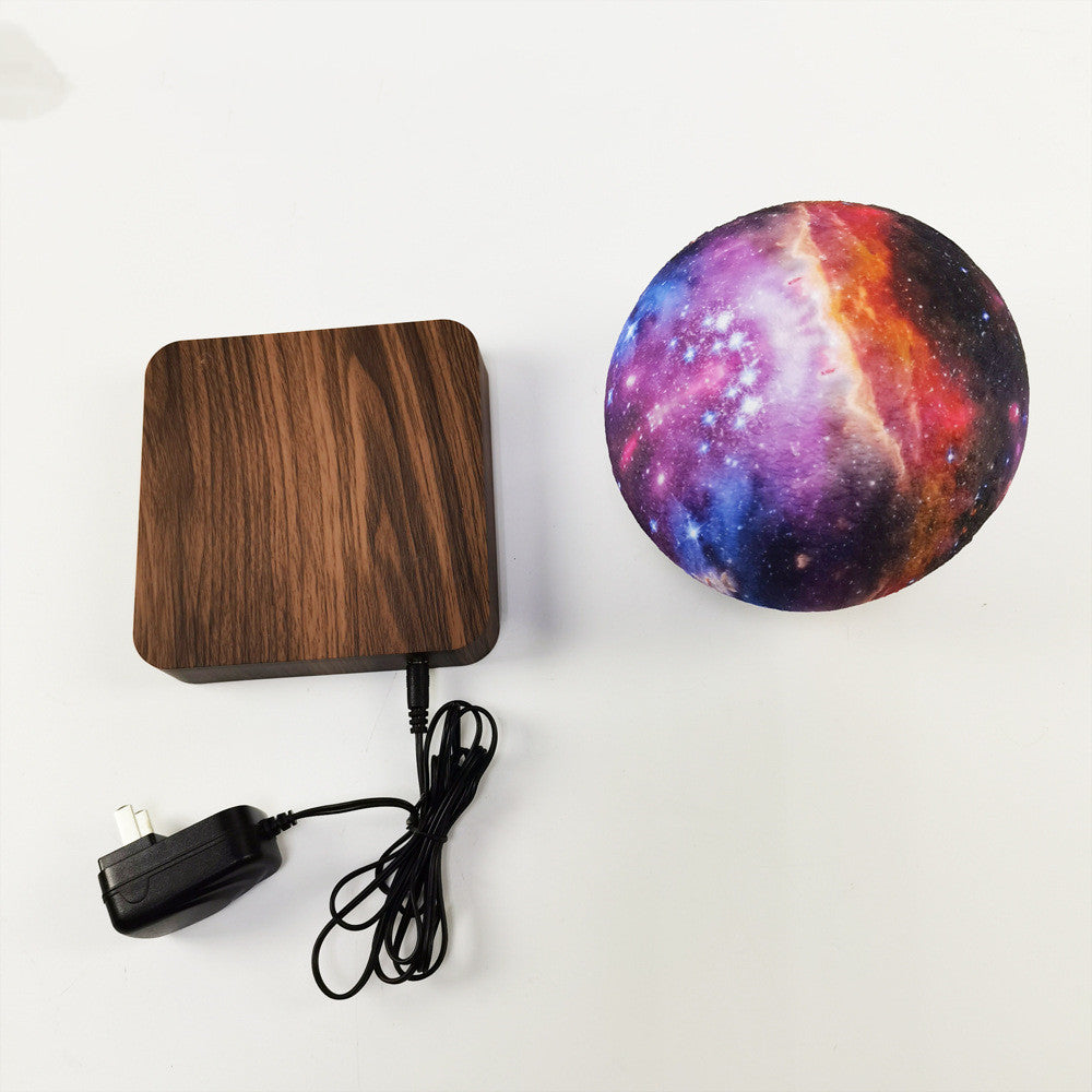 Wooden charging pad with cable and galaxy-patterned ball on a white background