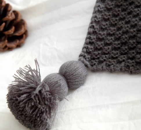 Gray knitted hat with pom-pom on a white background