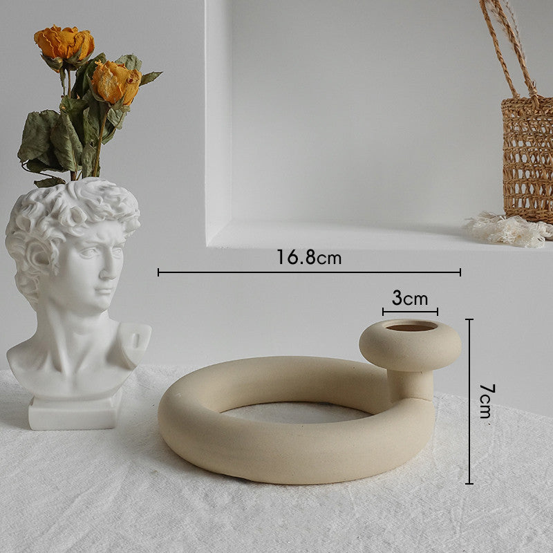 Ceramic vase shaped like a bust and a circular beige vase with measurements on a light gray background