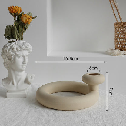 Ceramic vase shaped like a bust and a circular beige vase with measurements on a light gray background