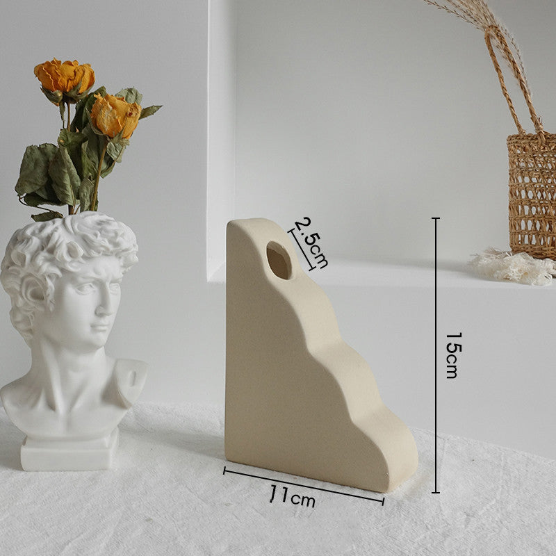 White stone sculpture with floral arrangement next to a beige stone sculpture with measurements on a light gray background