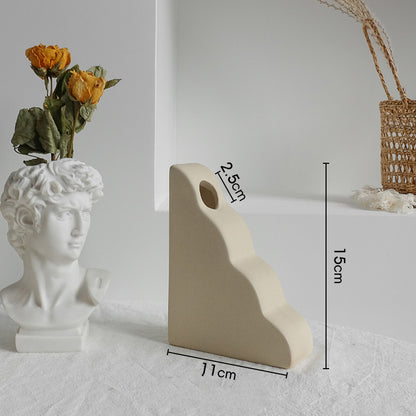 White stone sculpture with floral arrangement next to a beige stone sculpture with measurements on a light gray background