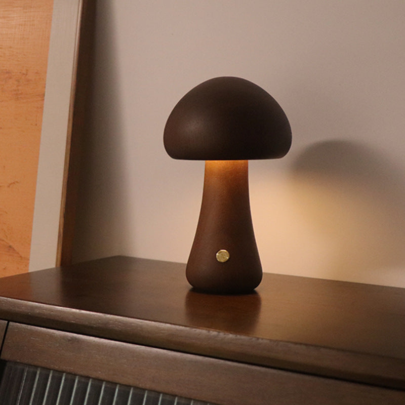 Mushroom-shaped table lamp on a wooden surface with warm lighting.
