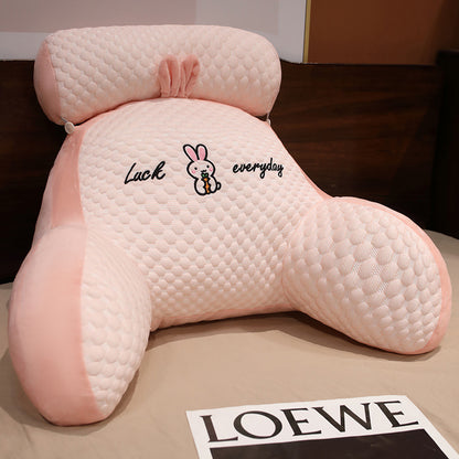 Pink backrest pillow with quilted texture and cartoon character on a surface.