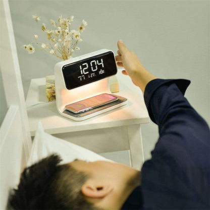 Person using a digital alarm clock on a nightstand with a smartphone below.