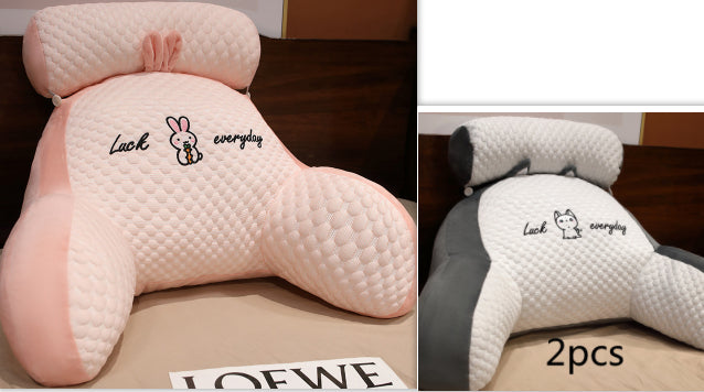Two pink and white neck pillows with cartoon designs on a wooden surface.