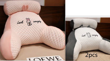 Two pink and white neck pillows with cartoon designs on a wooden surface.