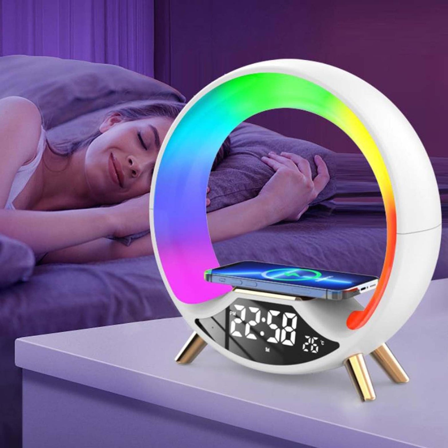 Multicolored night light with digital display and phone stand on a surface, with a person lying in bed in the background.