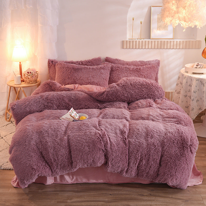 Pink fluffy comforter set on a bed in a cozy bedroom setting.