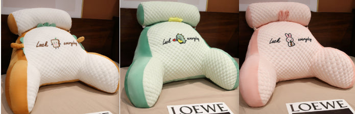 Three different colored pillows with text on a brown surface, featuring the brand 'LOEWE'.