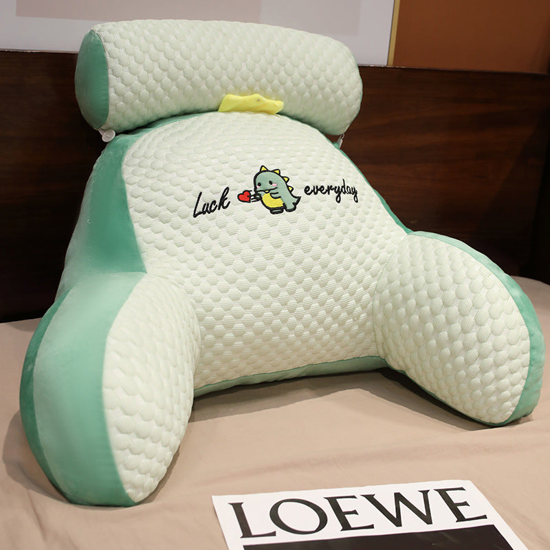Green and white pillow with a cartoon character and text on a brown surface with a Loewe brand name card.